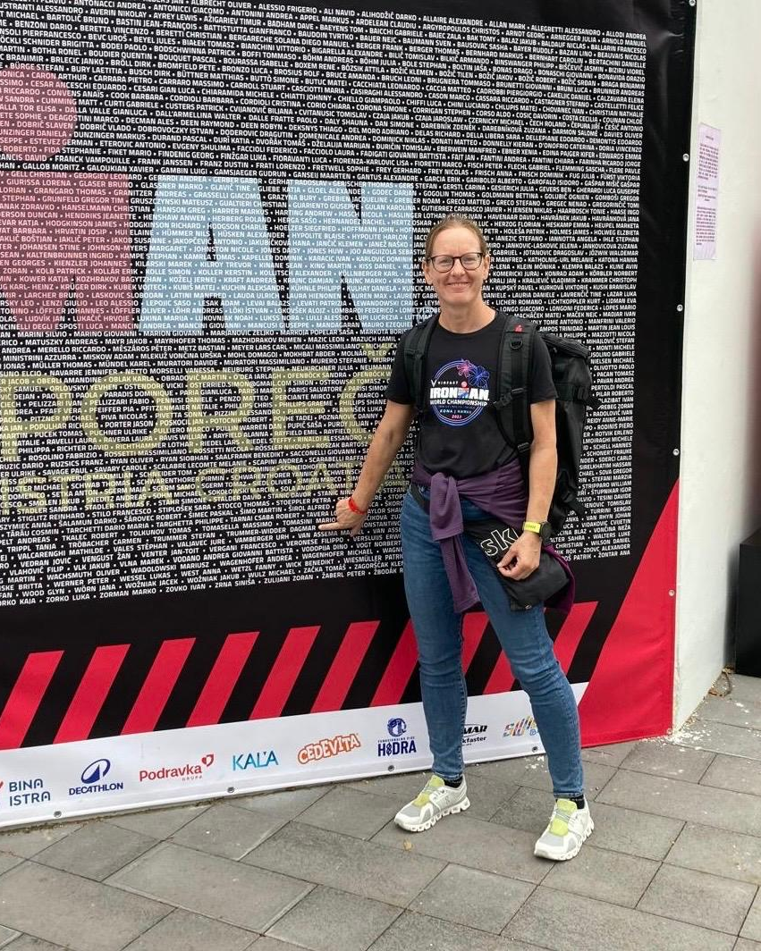 Dagmar, a long-term GFitness endurance athlete, in front of the Ironman World Championship start-list wall